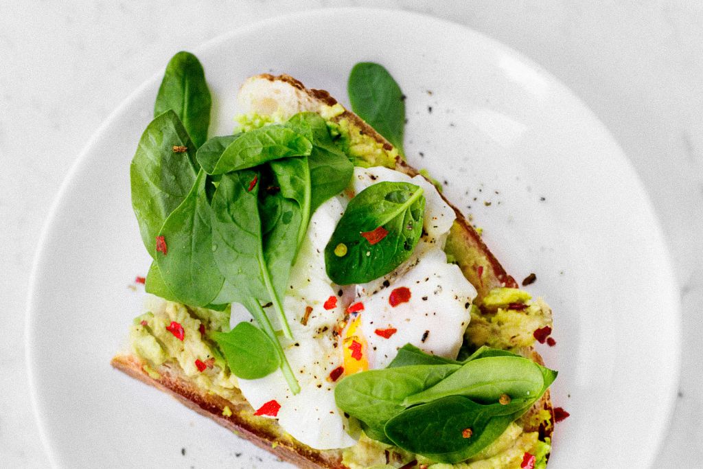 Vegan avocado toast on a plate with greens makes for the best vegan breakfast in NYC. 