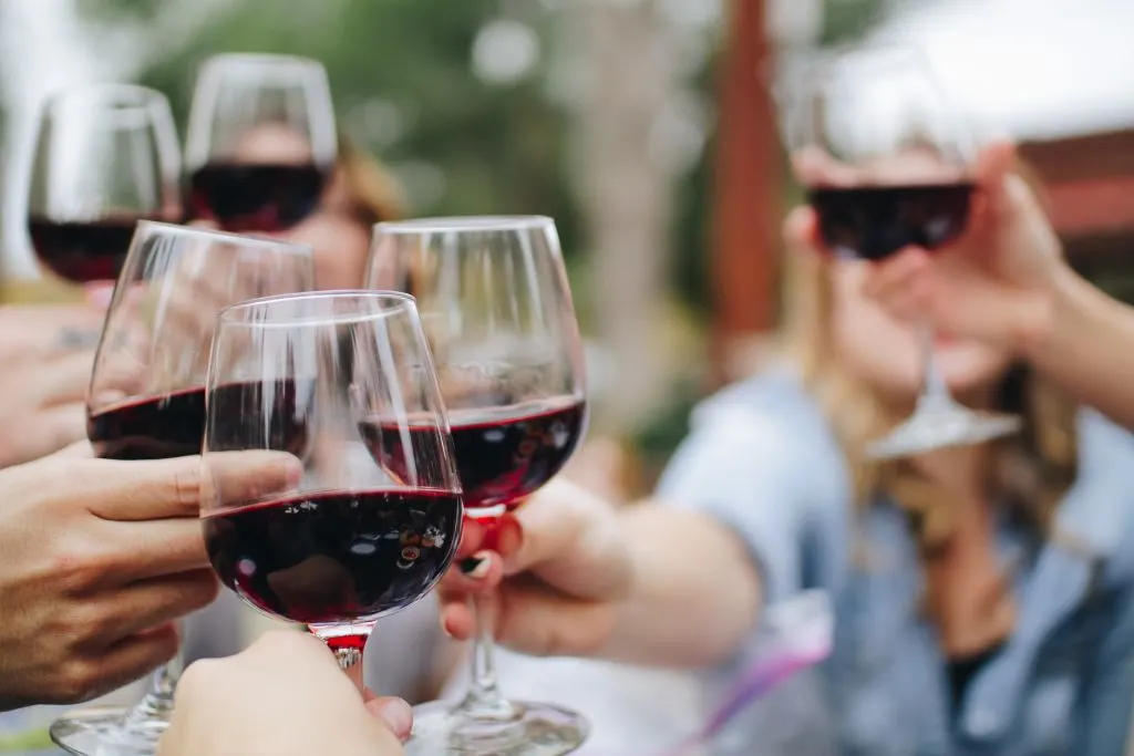 Friends raising glasses of red wine and making a toast. 