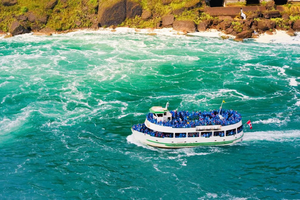 Aerial view of the Maid of the Mist boat tour in the water of Niagara Falls.