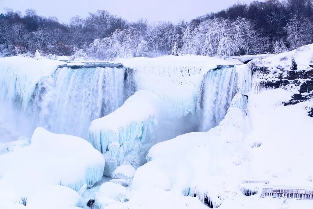Niagara Falls completely frozen and surrounded by snow in the winter during the best time to go to Niagara Falls. 