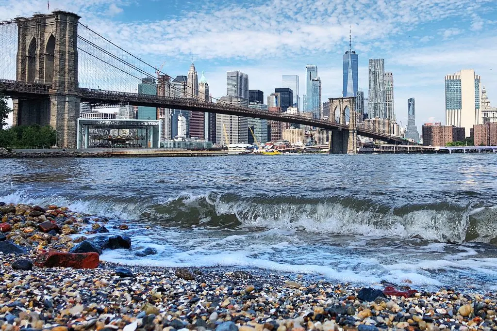View of the Manhattan skyline and Brooklyn Bridge from Pebble Beach in Dumbo. 