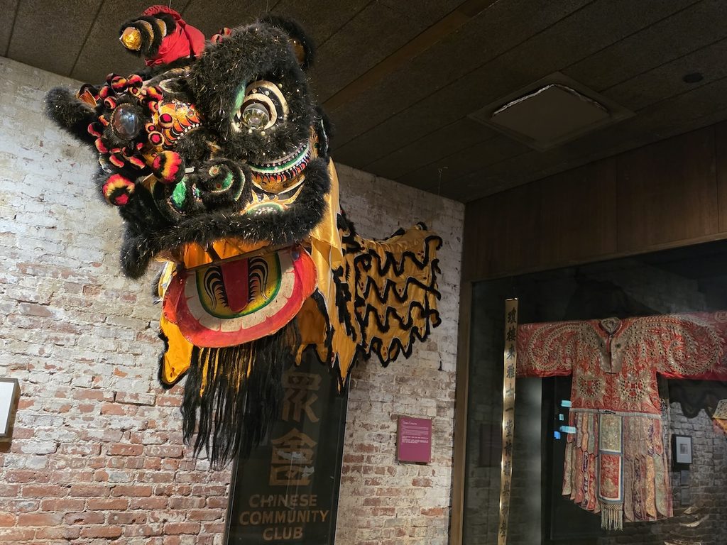 View of a Chinese dragon head and old traditional Chinese clothes hanging on display in MOCA.