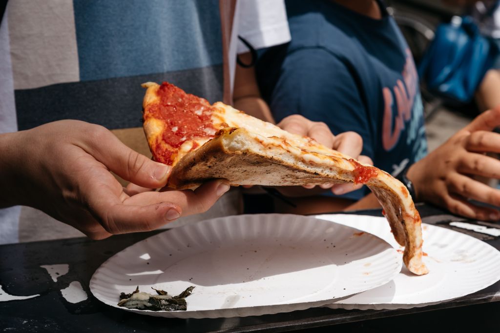 Person holding and eating a slice of pizza in NYC. 