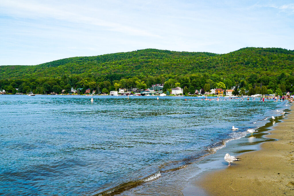 View of Million Dollar Beach on Lake George with boats on the water and people playing on the beach.