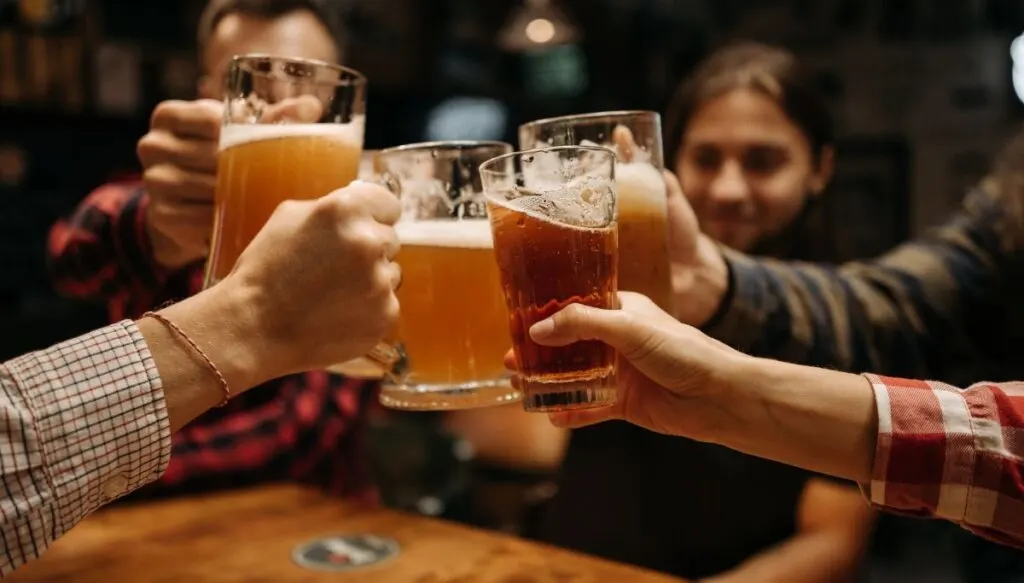 Four friends raising their beers together at one of the best Lake Placid breweries.