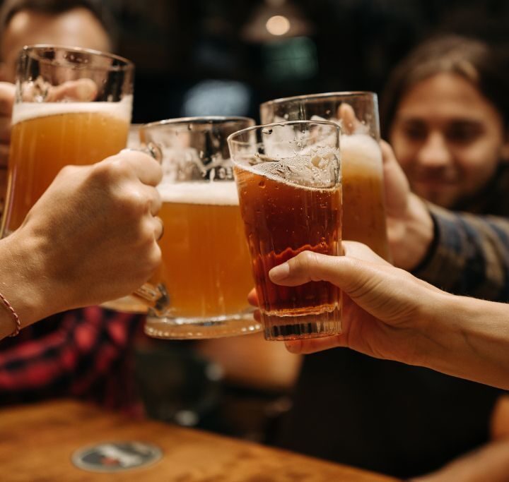 Four friends raising their beers together at one of the best Lake Placid breweries.