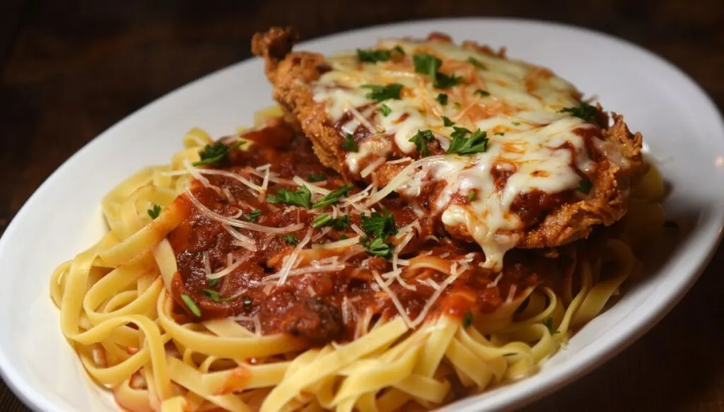 A giant plate of chicken parm. On it you'll find fried chicken smothered in cheese that sits on a bed of pasta with tomato sauce. 