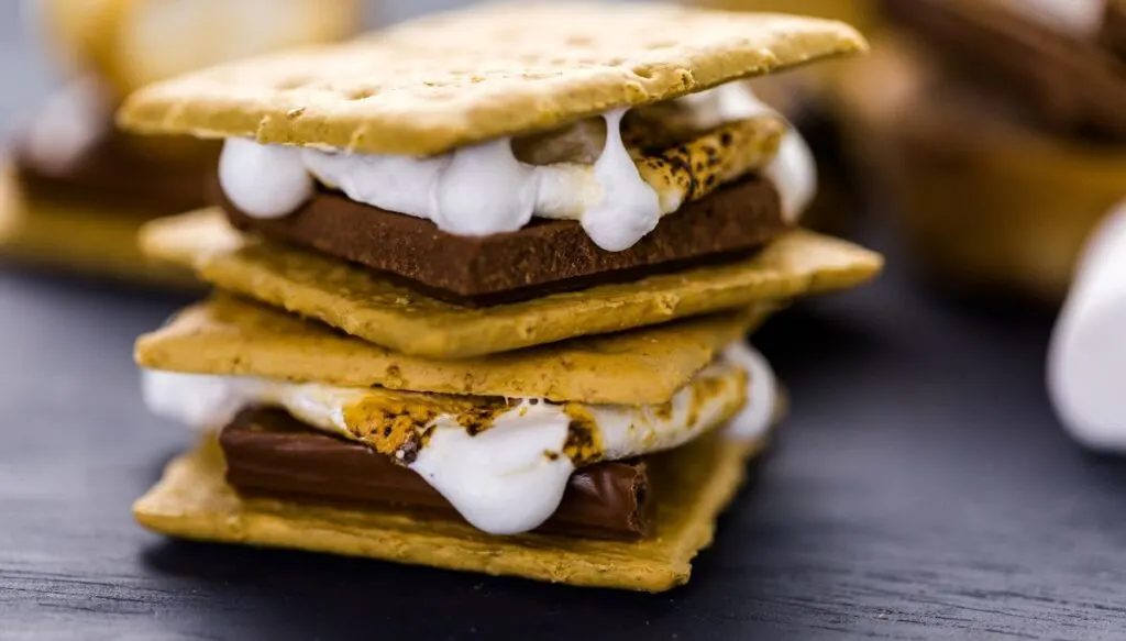 Two smores sitting on top of one another with milk chocolate and melted marshmellow in between graham crackers. 