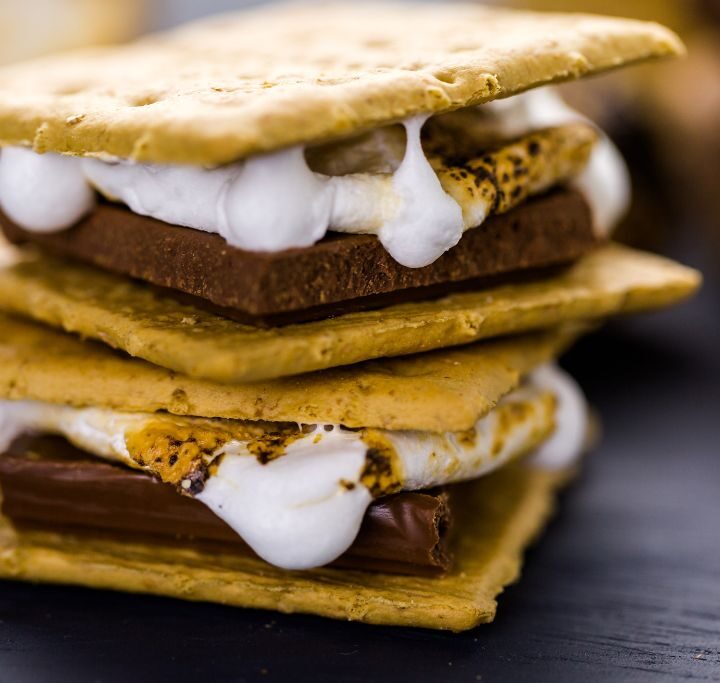 Two smores sitting on top of one another with milk chocolate and melted marshmellow in between graham crackers.
