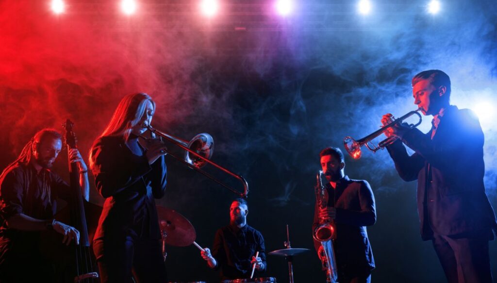 A jazz band playing the sax and other instruments in a smokey room with blue and red lights in New York City in January. 