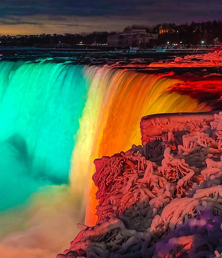 View of Niagara Falls at night all lit up with multi-color lights.