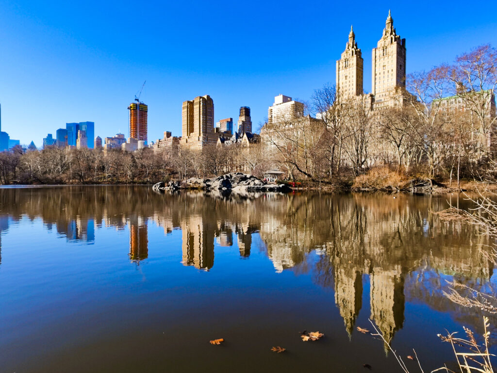 A view of Central Park in the winter with the skyscrapers on the West Side being reflected in the lake near the Ramble.