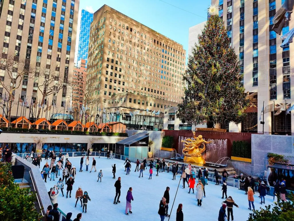 A photo of people skating at the rink in Rockefeller Center with the Christmas Tree standing above them. 