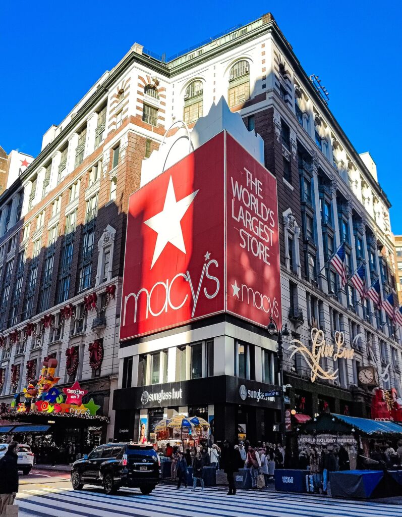 A view of Macy's at Herald's Square with a sign that is a red shopping bag. It is one ot the best places to go in NYC in March. 
